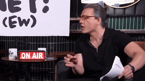 a man is sitting at a table with a sign that says on air