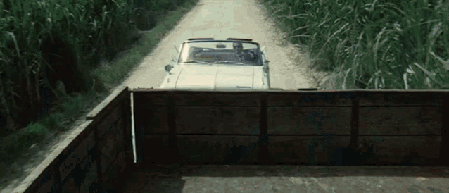 a car is driving down a dirt road next to a fence