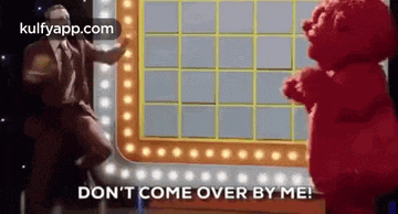 a man in a suit and tie is dancing next to a red teddy bear on a game show .