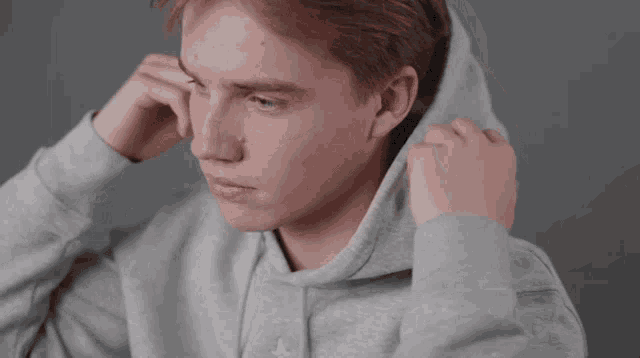a young man wearing a grey hoodie with the letter a embroidered on it