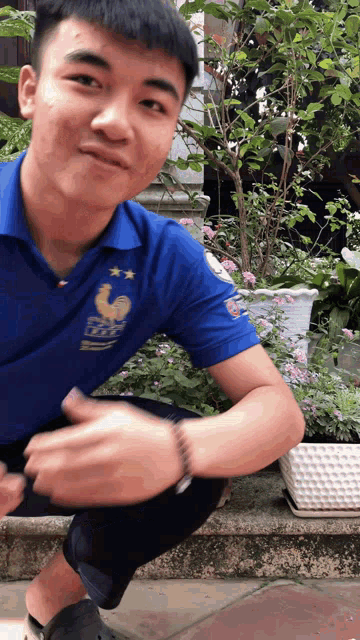 a young man wearing a blue shirt with a rooster on the front