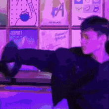 a man is standing in front of a purple wall holding a purple object in his hand .