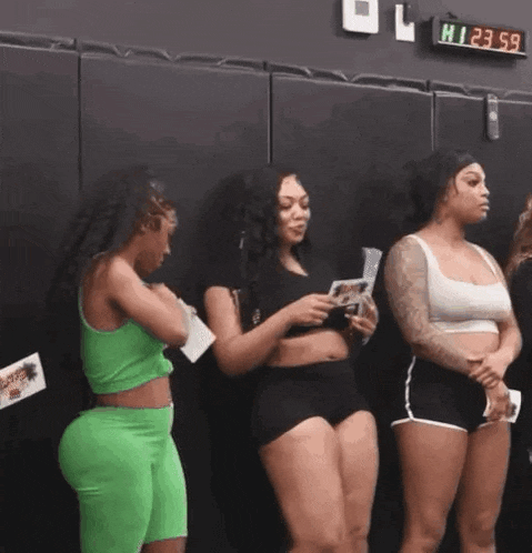 a group of three women are standing next to each other in a gym .