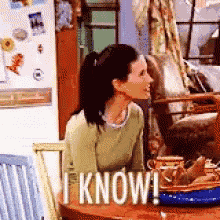 a woman sitting at a table with a sign that says i know .