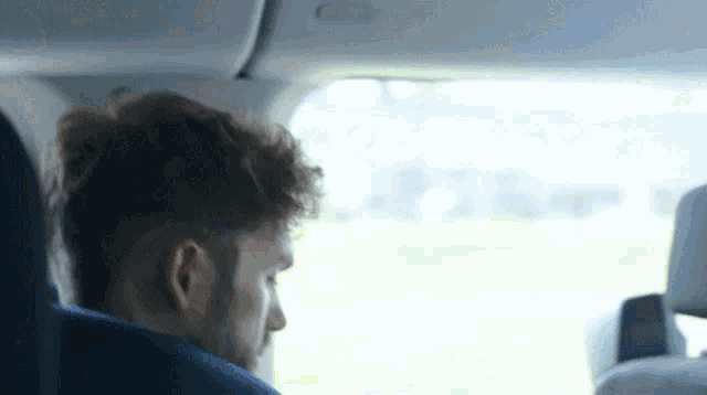 a man is sitting in the back seat of a car and looking out the window
