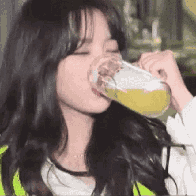 a woman is drinking a glass of beer from a glass .