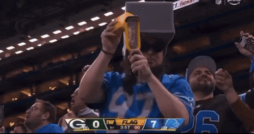 a man wearing a virtual reality headset watches a football game between the lions and the giants