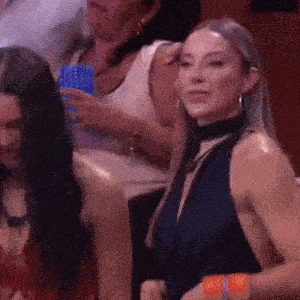 a woman in a blue dress is sitting in a crowd of people and looking at the camera .