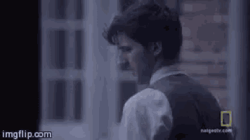 a man is standing in front of a window in a dark room .