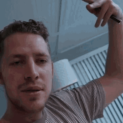 a man in a striped t-shirt is pointing his finger at the camera .