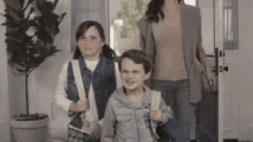a woman and two children are walking into a doorway .