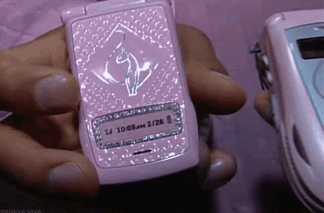 a person holding a pink flip phone that says 10:08 am on it