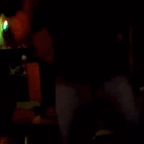 a blurry picture of a man in a dark room with blue lights behind him