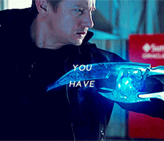 a man in a black jacket is holding a blue object that says " you have "