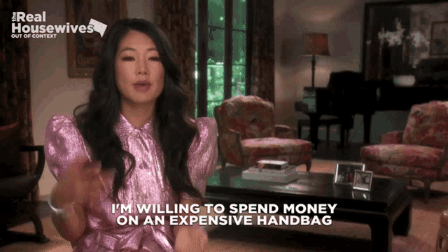 a woman in a pink dress talks about spending money on an expensive handbag