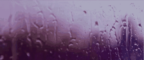 rain drops on a window with a purple background .