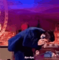 a man is singing into a microphone while kneeling down .