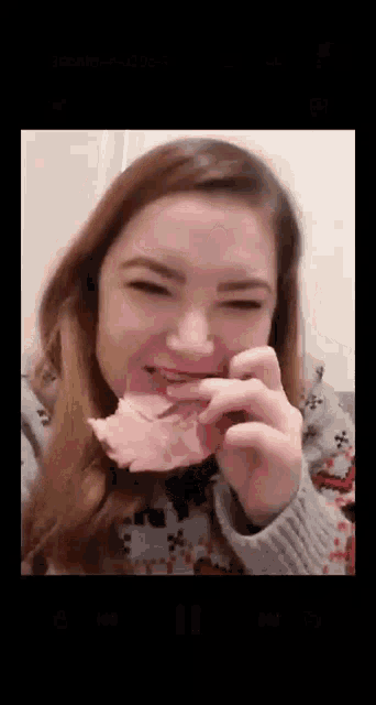 a woman is eating a piece of meat with her mouth open