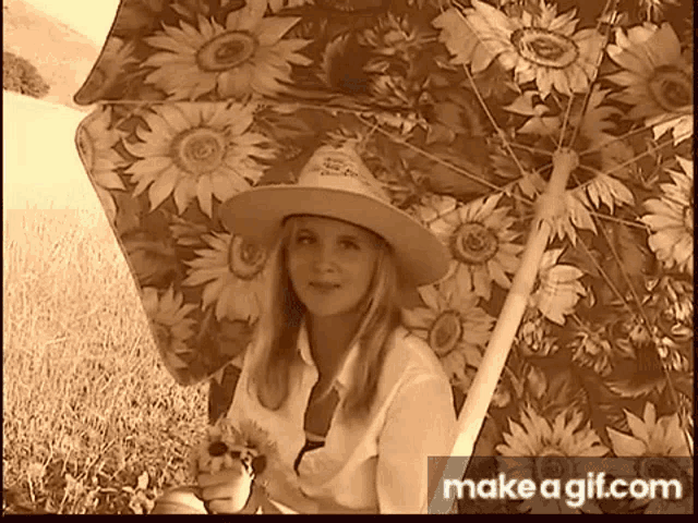 a woman in a cowboy hat is holding a sunflower under an umbrella