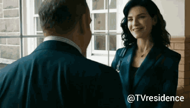 a woman in a blue suit is smiling at a man