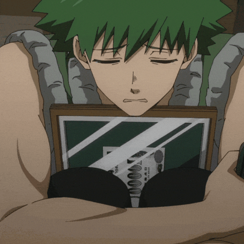 a man with green hair is laying down with his eyes closed and looking at a picture with a foreign language on it