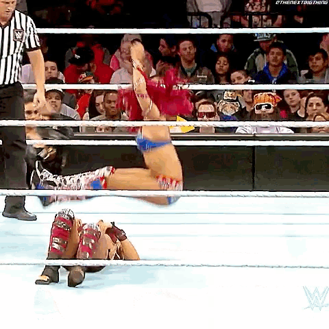 a wrestler is falling through the ropes in a wrestling ring