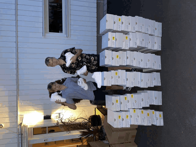 two people standing in front of a stack of boxes with a yellow label that says ' socks '