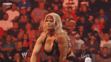a female wrestler is standing in front of a crowd with a wwe logo on the screen