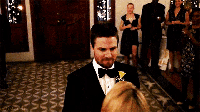 a man in a tuxedo is standing next to a woman in a dress .
