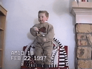 a young boy is standing in front of a fireplace with the date february 22 1997