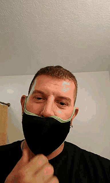 a man is wearing a black face mask with green trim