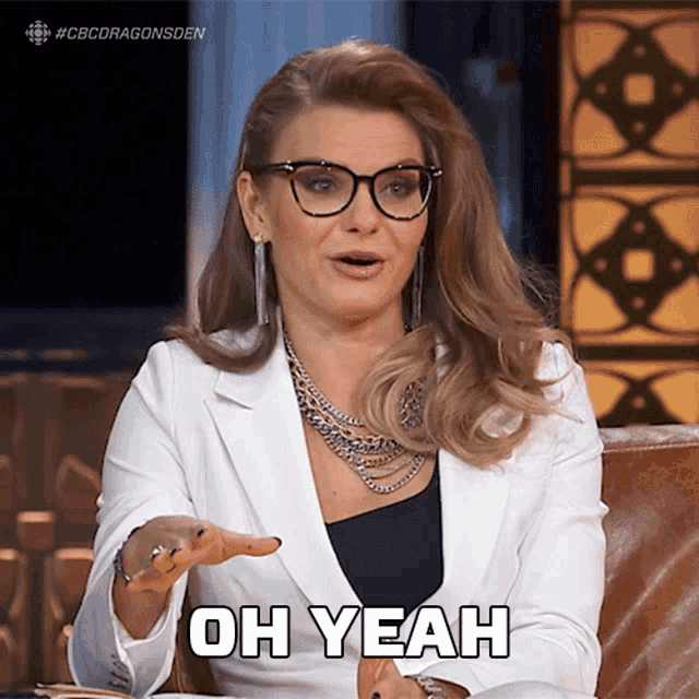 a woman wearing glasses and a white jacket is saying oh yeah