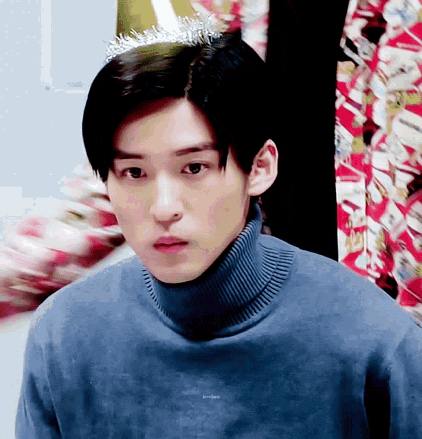a young man wearing a blue sweater and a tiara