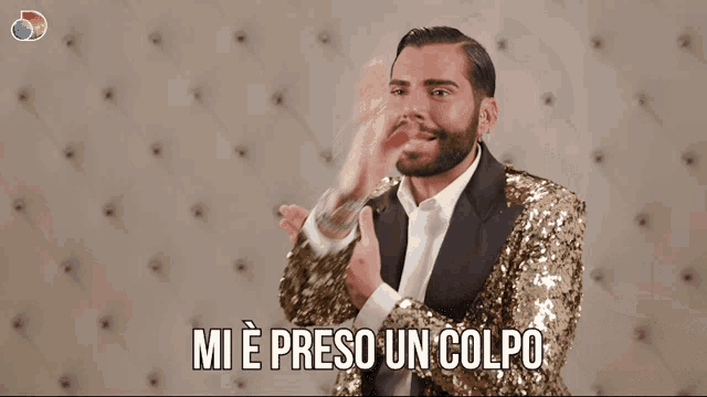 a man in a gold sequined suit is clapping his hands and the words mi e preso un colpo are above him