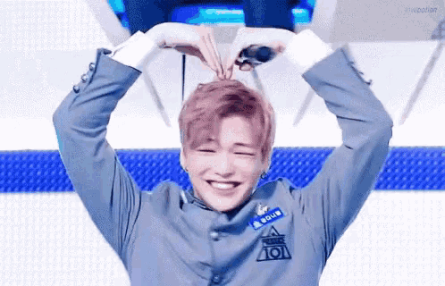 a young man is making a heart shape with his hands while smiling .