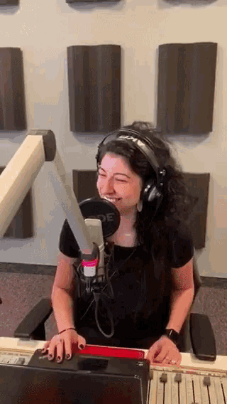 a woman wearing headphones is sitting in front of a microphone