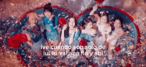 a group of girls are laying on top of each other in a heart shaped pool of confetti .