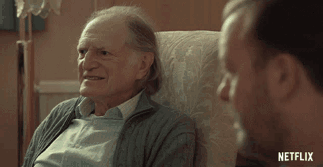 an older man is sitting in a chair talking to another man with netflix written on the bottom