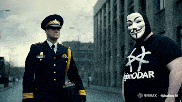 a man wearing a legion odar shirt stands next to a police officer