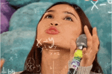 a woman holds a microphone in front of a chalkboard with math equations