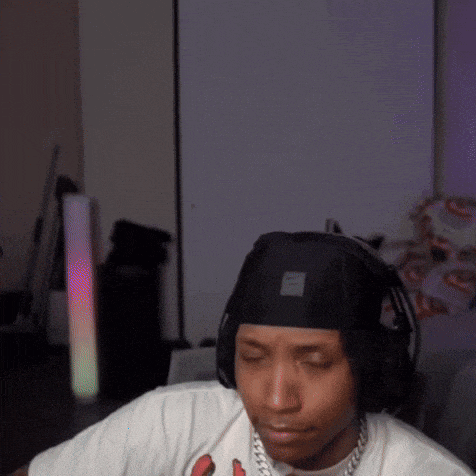 a man wearing headphones and a bandana is sitting in a room with his eyes closed .