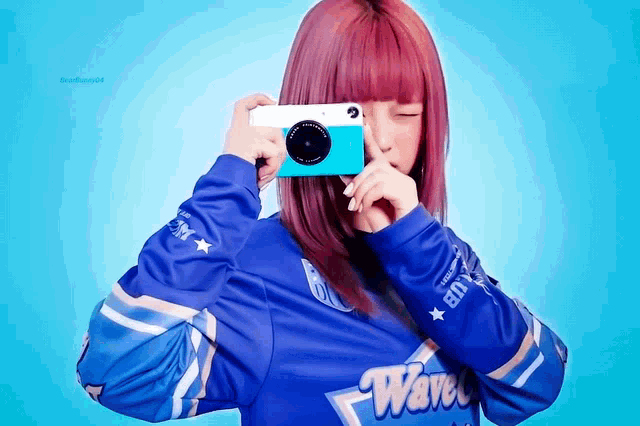 a girl wearing a blue wave jersey is taking a picture with a camera