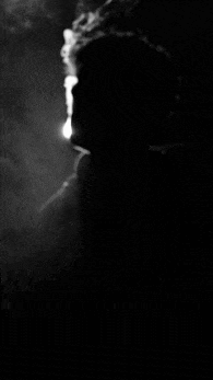 a black and white photo of a person smoking a cigarette .