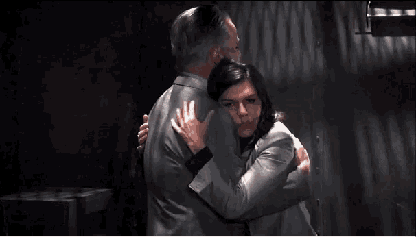 a man and a woman are standing next to each other in a dark room and kissing .