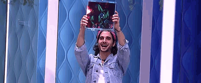 a man in a denim jacket is holding up a picture of a rabbit