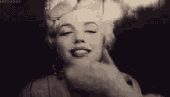 a black and white photo of marilyn monroe making a funny face with her eyes closed .