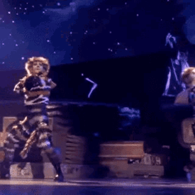 a couple of people are dancing on a stage in front of a crowd .