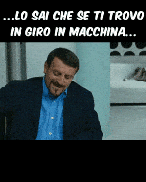 a man in a suit and blue shirt is sitting in front of a sign that says lo sai che se ti trova