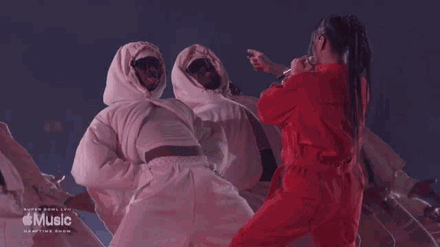 a woman in a red jumpsuit is standing in front of a group of people in white jumpsuits