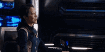 a woman in a star trek uniform is talking to someone and says are you fucking kidding me right now .